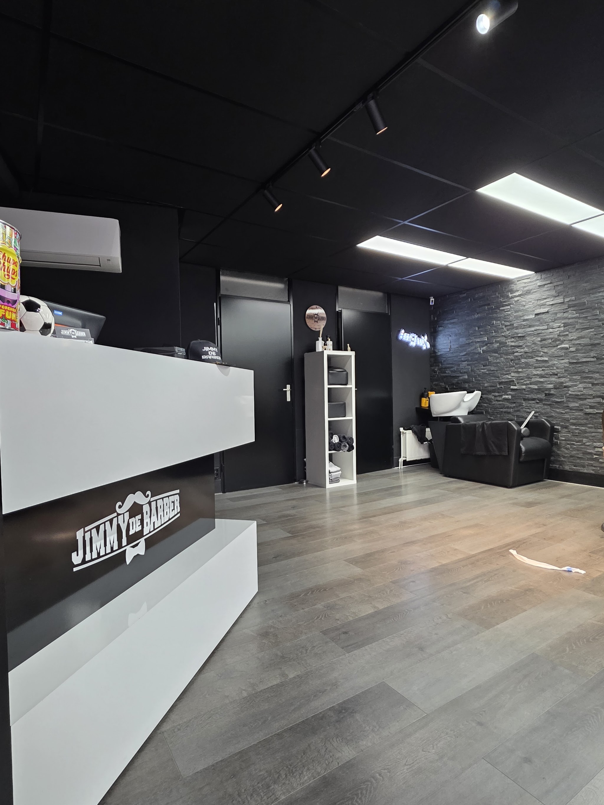 De zaak van binnen: witte balie met het bord van Jimmy de Barber, zwarte wand en lichte vloer